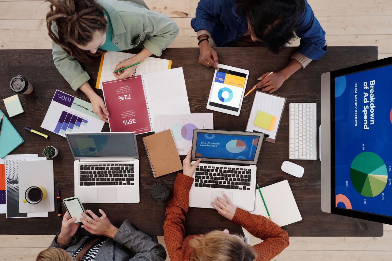 A diverse team working together on digital marketing strategies at a desk, using laptops and tablets.